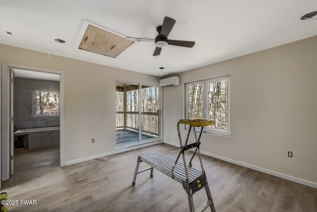 misc room with wood-type flooring, an AC wall unit, and a healthy amount of sunlight