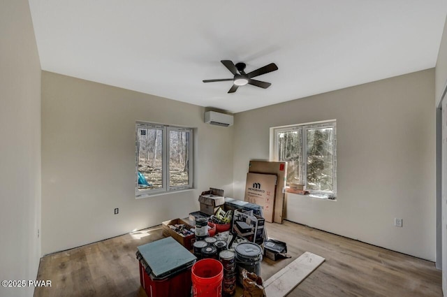 interior space with a wall mounted air conditioner, ceiling fan, and light hardwood / wood-style flooring