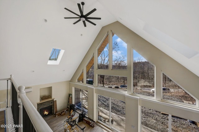 living room with hardwood / wood-style flooring, a skylight, and high vaulted ceiling