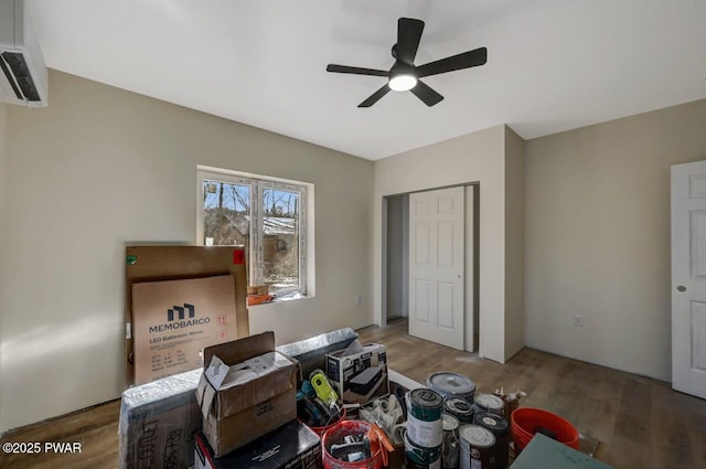 bedroom with hardwood / wood-style flooring, an AC wall unit, ceiling fan, and a closet