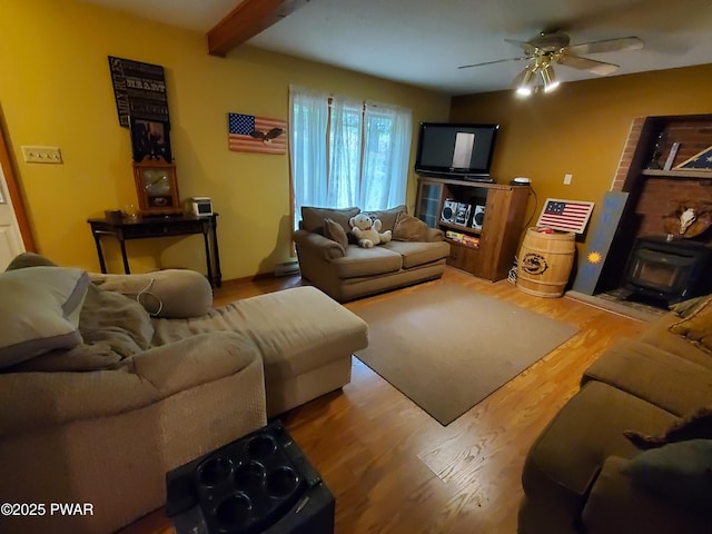 188 Forest Ridge Dr, Hawley, PA 18428 - living area featuring a ceiling fan, wood finished floors, beamed ceiling, and a wood stove
