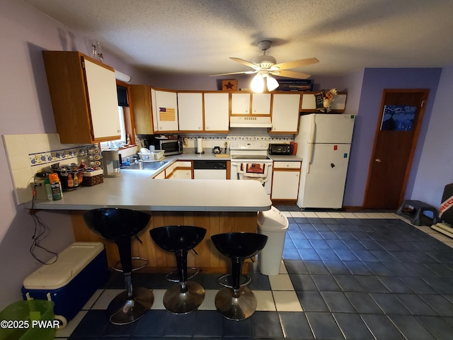 188 Forest Ridge Dr, Hawley, PA 18428 - kitchen with white appliances, under cabinet range hood, a peninsula, backsplash, and a ceiling fan