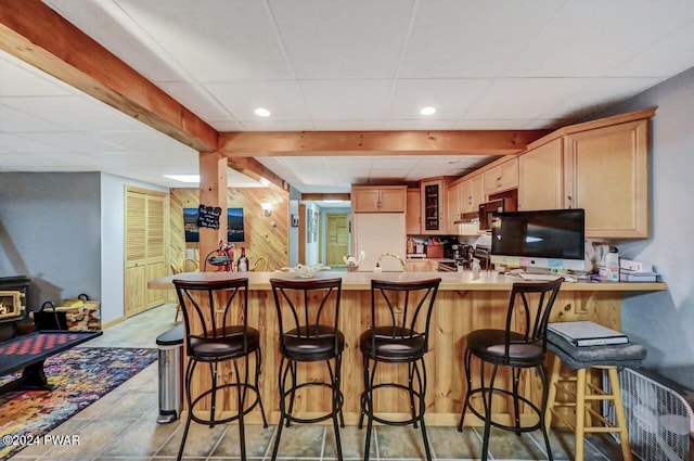 kitchen featuring a paneled ceiling, a wood stove, light brown cabinets, kitchen peninsula, and white fridge