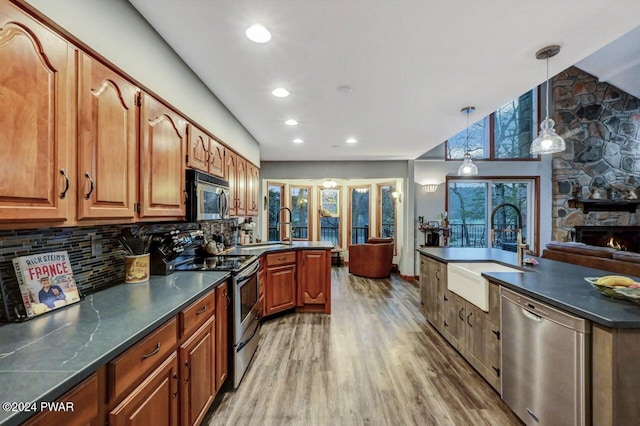 kitchen with appliances with stainless steel finishes, hardwood / wood-style floors, sink, backsplash, and hanging light fixtures