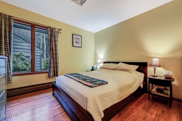 bedroom featuring hardwood / wood-style flooring and a baseboard heating unit