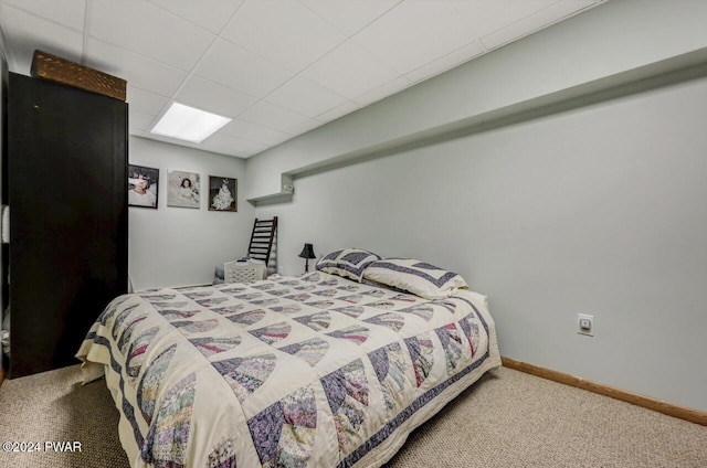 bedroom featuring a drop ceiling and carpet floors