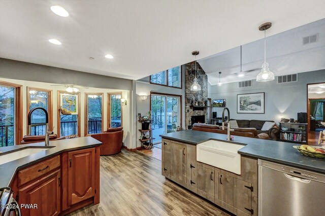 kitchen with pendant lighting, stainless steel dishwasher, sink, and light wood-type flooring