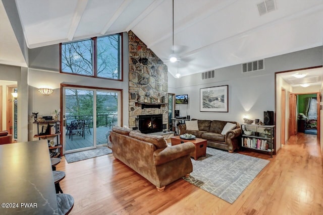 living room with a stone fireplace, high vaulted ceiling, light hardwood / wood-style flooring, beamed ceiling, and ceiling fan