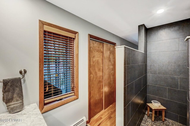 bathroom featuring a baseboard heating unit and tiled shower