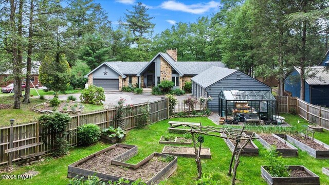 122 Waterfront Dr, Greentown, PA 18426 - fenced backyard featuring a vegetable garden, a garage, asphalt driveway, a greenhouse, and an outbuilding