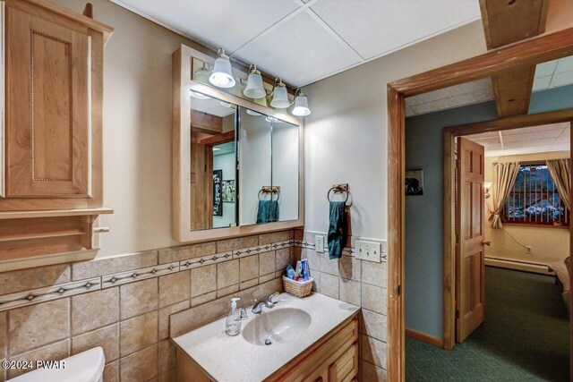 bathroom featuring vanity, a baseboard heating unit, toilet, and tile walls