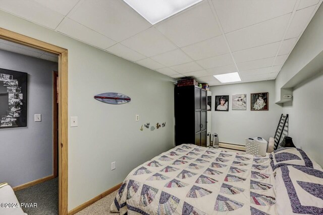 bedroom with carpet flooring, a drop ceiling, and baseboard heating