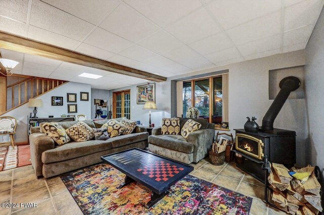 tiled living room with a paneled ceiling and a wood stove