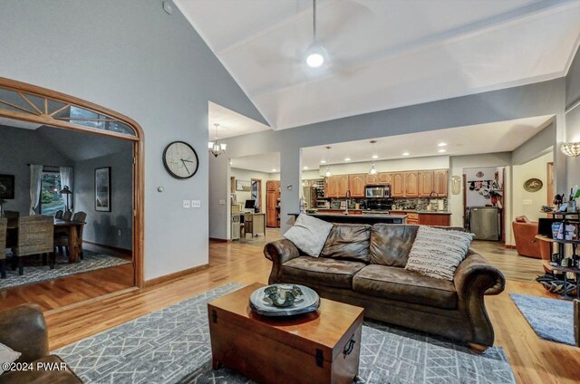 living room featuring a notable chandelier, light hardwood / wood-style flooring, and high vaulted ceiling