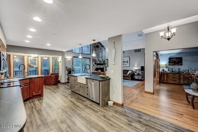 kitchen with appliances with stainless steel finishes, sink, hanging light fixtures, a notable chandelier, and light wood-type flooring