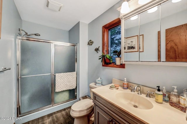 bathroom featuring vanity, an enclosed shower, wood-type flooring, and toilet