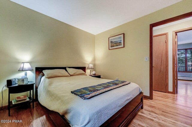 bedroom featuring light hardwood / wood-style floors and a baseboard heating unit