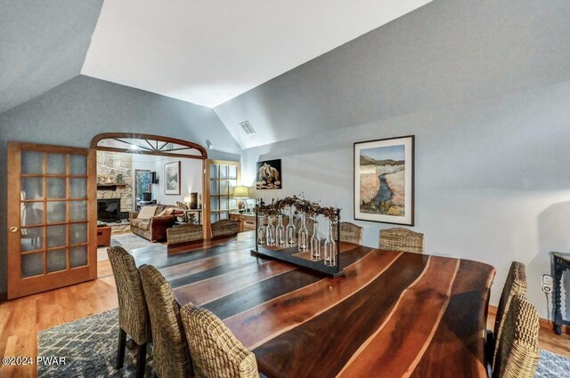 dining room with hardwood / wood-style flooring, a fireplace, and vaulted ceiling