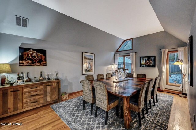 dining area featuring a healthy amount of sunlight, vaulted ceiling, and light hardwood / wood-style flooring