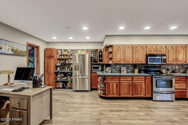 kitchen with tasteful backsplash, appliances with stainless steel finishes, and light hardwood / wood-style flooring