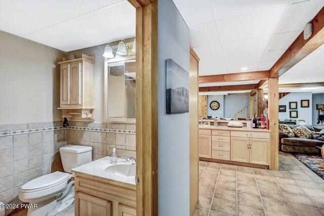 bathroom featuring vanity, toilet, and tile walls