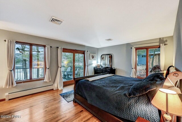 bedroom with a baseboard heating unit, access to outside, and light hardwood / wood-style floors