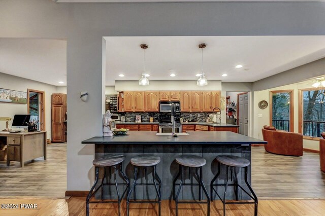 kitchen with pendant lighting, stainless steel appliances, kitchen peninsula, and a breakfast bar area