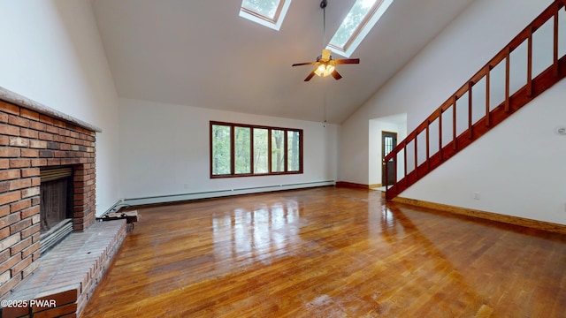 158 Wild Meadow Dr, Milford, PA 18337 - unfurnished living room with a baseboard radiator, high vaulted ceiling, a brick fireplace, wood finished floors, and a skylight