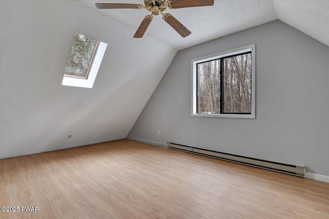 bonus room with lofted ceiling with skylight, light hardwood / wood-style floors, a textured ceiling, and baseboard heating