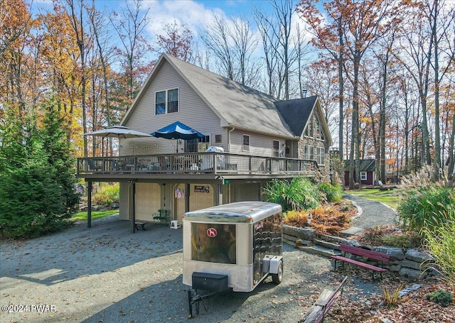 rear view of property with a wooden deck and a garage