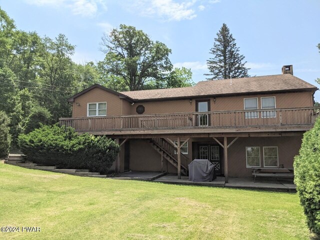 rear view of house featuring a patio, a deck, and a lawn