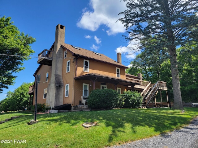 rear view of house featuring a lawn and a wooden deck