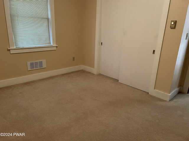 unfurnished bedroom featuring light carpet and a closet