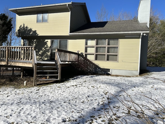 snow covered back of property featuring a wooden deck