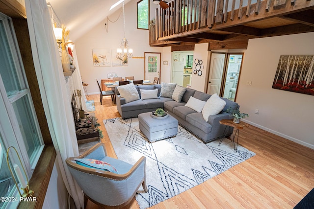 living room featuring vaulted ceiling, an inviting chandelier, and light hardwood / wood-style flooring