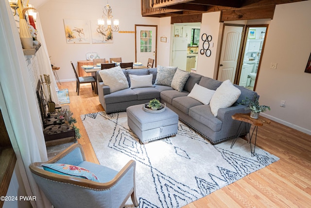 living room with beam ceiling, light hardwood / wood-style floors, and an inviting chandelier