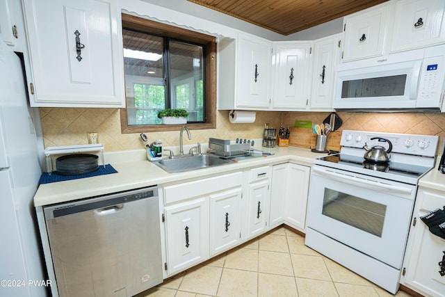 kitchen with white cabinets, light tile patterned flooring, white appliances, and sink