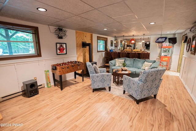 living room with a paneled ceiling, hardwood / wood-style floors, and a wood stove