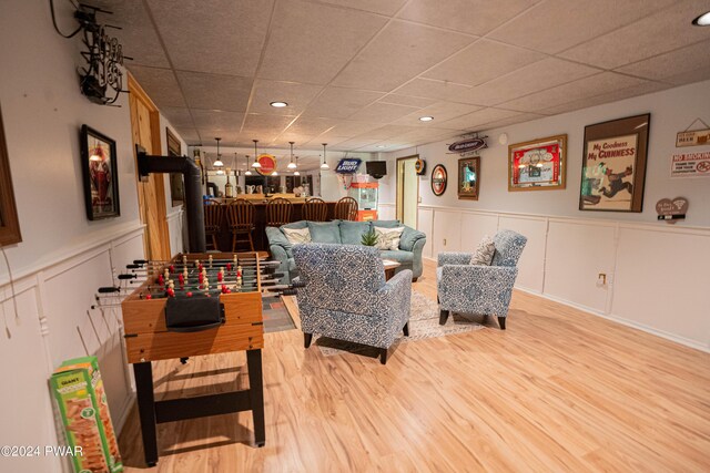 living room with a paneled ceiling and light wood-type flooring