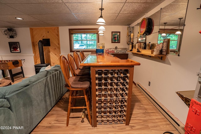 dining room featuring a paneled ceiling, wood-type flooring, indoor bar, and a baseboard heating unit