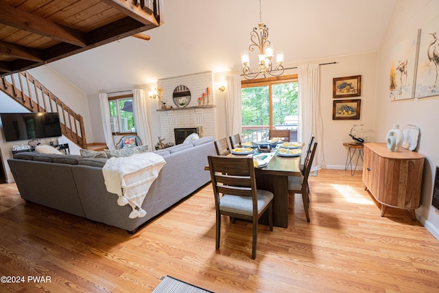 dining room with hardwood / wood-style flooring, vaulted ceiling with beams, a fireplace, and a wealth of natural light