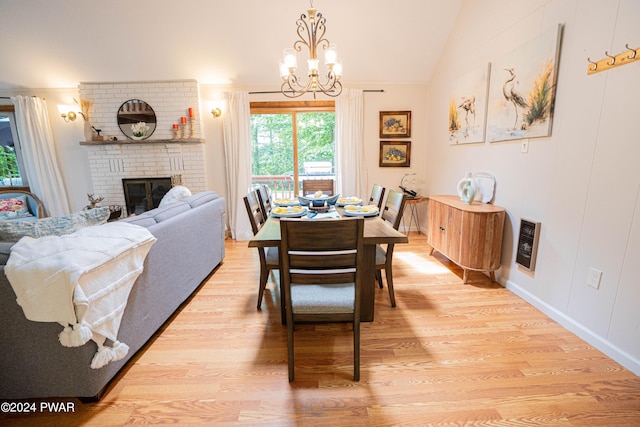 dining area featuring lofted ceiling, a brick fireplace, light wood-type flooring, a notable chandelier, and heating unit