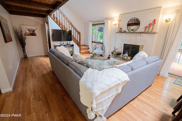 living room featuring beamed ceiling, wood ceiling, a fireplace, and hardwood / wood-style flooring