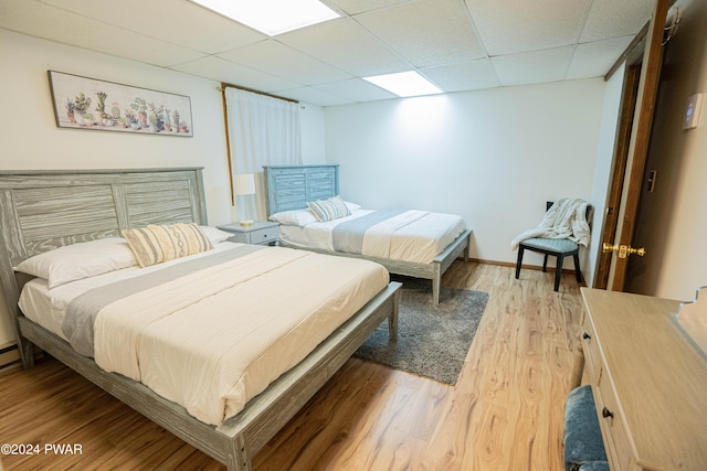 bedroom featuring a paneled ceiling and light hardwood / wood-style flooring