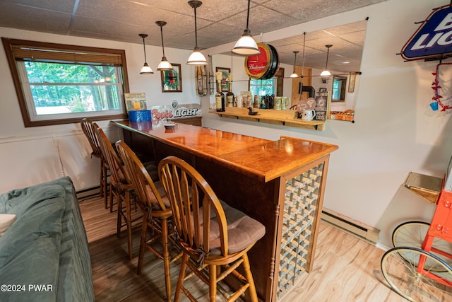 bar with a paneled ceiling, wood counters, baseboard heating, and hardwood / wood-style flooring