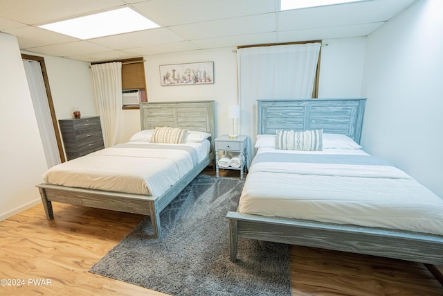 bedroom with a drop ceiling and hardwood / wood-style flooring