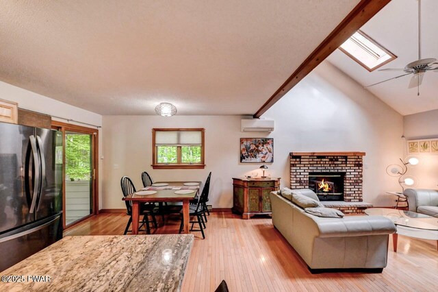 105 Chestnut Ct, Lackawaxen, PA 18435 - living area with an AC wall unit, light wood finished floors, a skylight, a fireplace, and ceiling fan