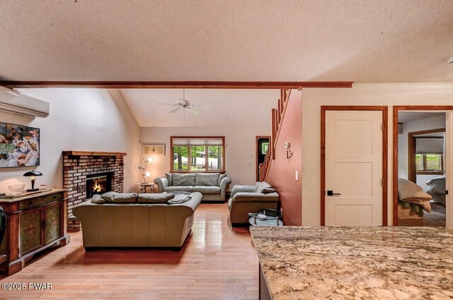 105 Chestnut Ct, Lackawaxen, PA 18435 - living area with ceiling fan, light wood-style flooring, a wall unit AC, a textured ceiling, and a brick fireplace