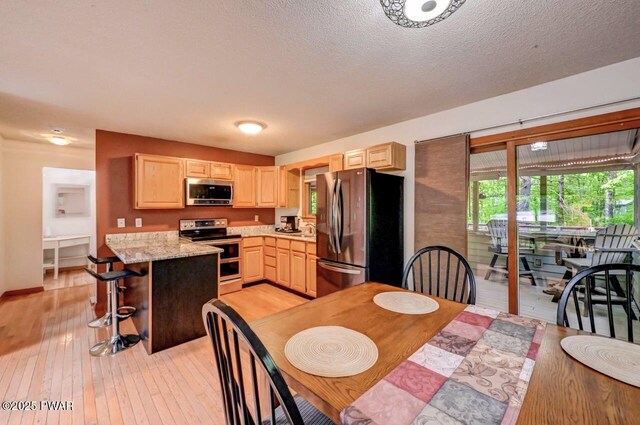105 Chestnut Ct, Lackawaxen, PA 18435 - kitchen featuring stainless steel appliances, light brown cabinetry, light wood-style floors, a breakfast bar, and a peninsula
