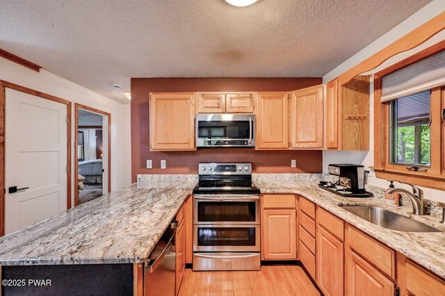 105 Chestnut Ct, Lackawaxen, PA 18435 - kitchen featuring stainless steel appliances, a sink, light brown cabinets, light wood-style floors, and a textured ceiling